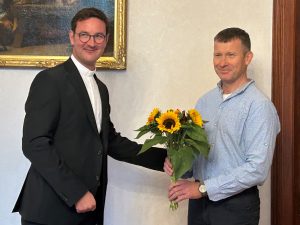 Ferdinand Liedtke wird mit einem Blumenstrauß von Generalvikar Markus Kurzweil begrüßt